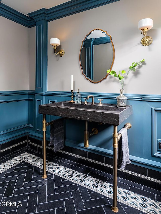 bathroom featuring a wainscoted wall, ornamental molding, and a decorative wall