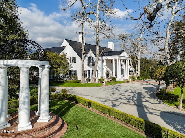 exterior space with a chimney, a front lawn, and stucco siding