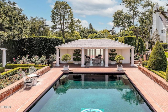 pool with a storage structure, a patio, and an outbuilding