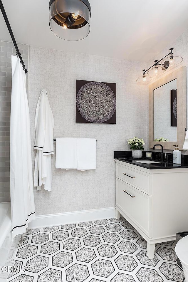 bathroom with shower / tub combo, baseboards, and vanity