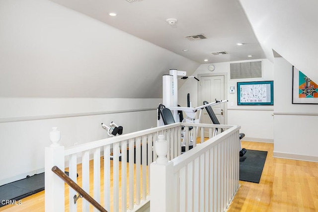 hallway with visible vents, an upstairs landing, and wood finished floors