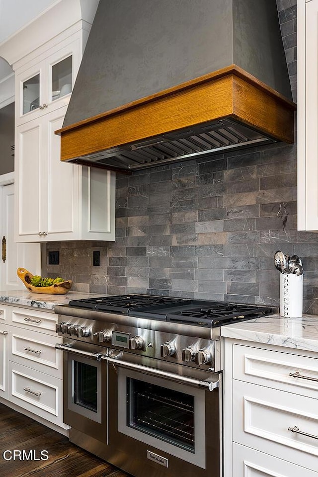 kitchen featuring white cabinets, premium range hood, glass insert cabinets, and range with two ovens