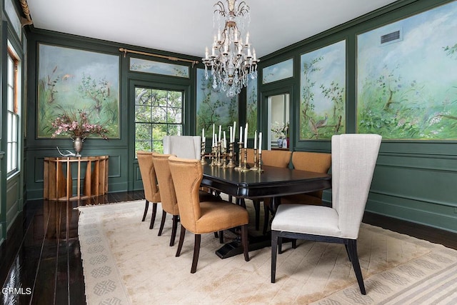 dining room featuring a notable chandelier, wood finished floors, visible vents, and a decorative wall