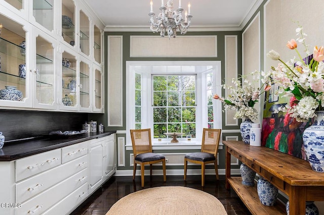 sitting room with baseboards, ornamental molding, a chandelier, and dark wood-type flooring