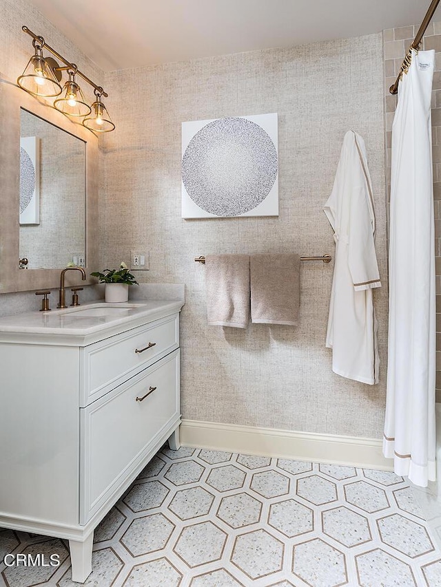 bathroom featuring a tile shower, vanity, and baseboards