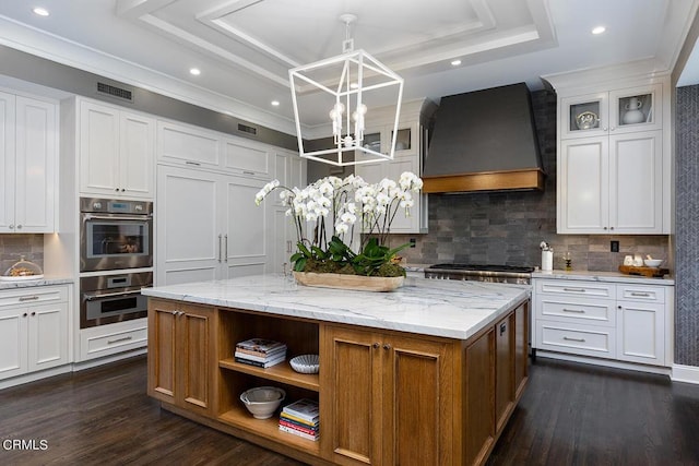 kitchen with a kitchen island, glass insert cabinets, a tray ceiling, premium range hood, and white cabinetry