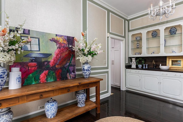 kitchen with white cabinets, dark countertops, glass insert cabinets, a chandelier, and a sink