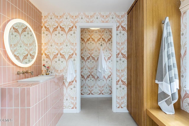 bathroom featuring tile patterned flooring, a sink, baseboards, and wallpapered walls