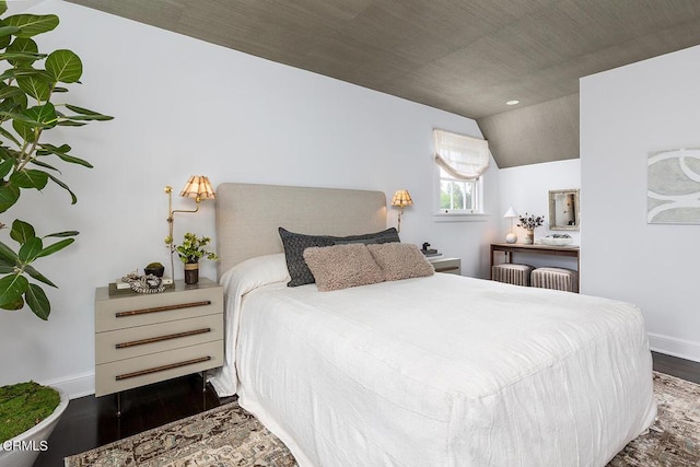 bedroom with dark wood-style flooring, vaulted ceiling, and baseboards