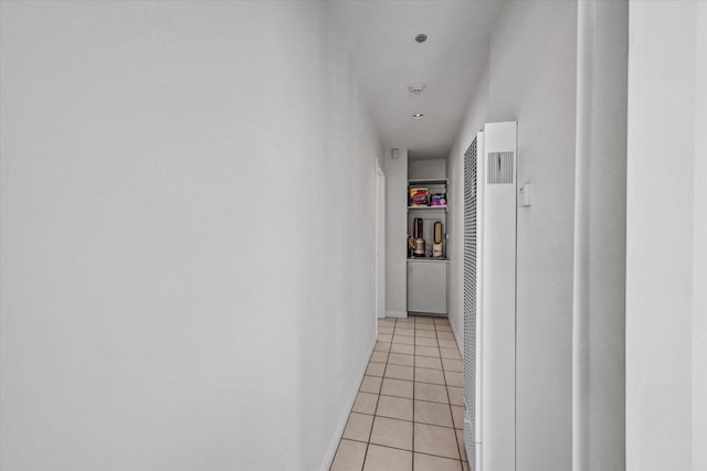 hall featuring a heating unit, light tile patterned flooring, and baseboards