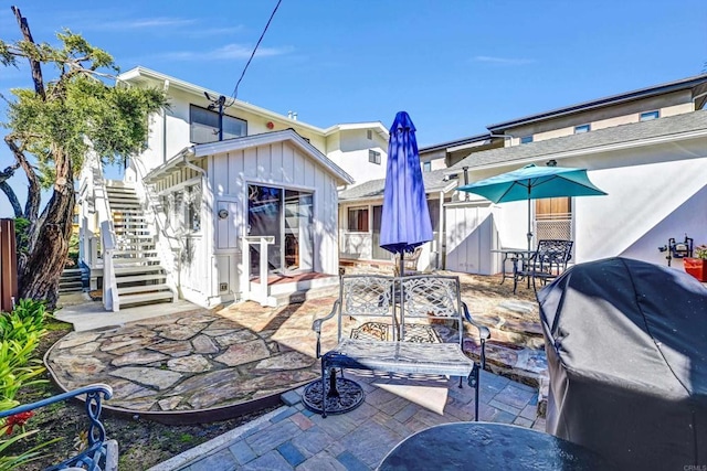 back of property featuring stairs, fence, board and batten siding, and a patio