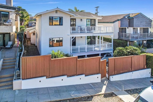 view of front of home with a fenced front yard, a balcony, and stucco siding