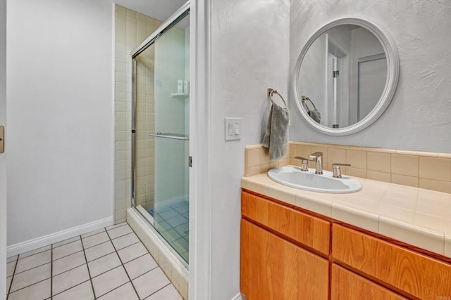 bathroom with baseboards, a stall shower, vanity, and tile patterned floors