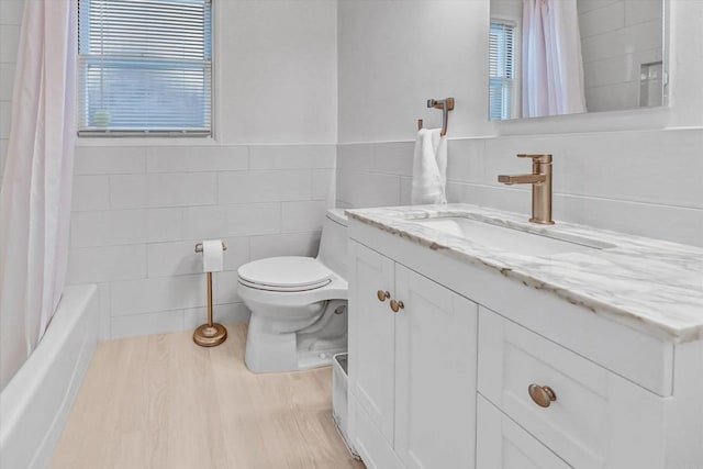 full bathroom with tile walls, toilet, shower / tub combo, vanity, and wood finished floors