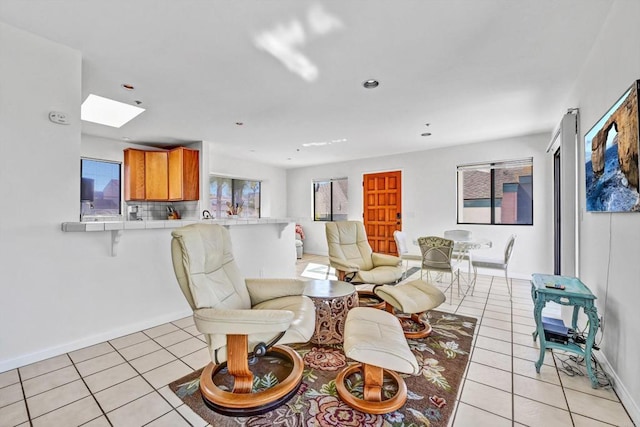 living area with light tile patterned floors, recessed lighting, a skylight, and baseboards