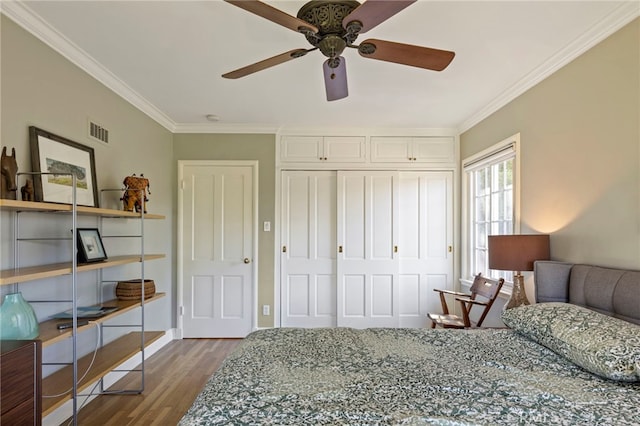 bedroom with a closet, visible vents, ornamental molding, wood finished floors, and baseboards