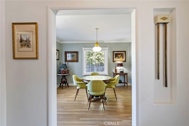 dining space with crown molding, light wood-style flooring, and baseboards