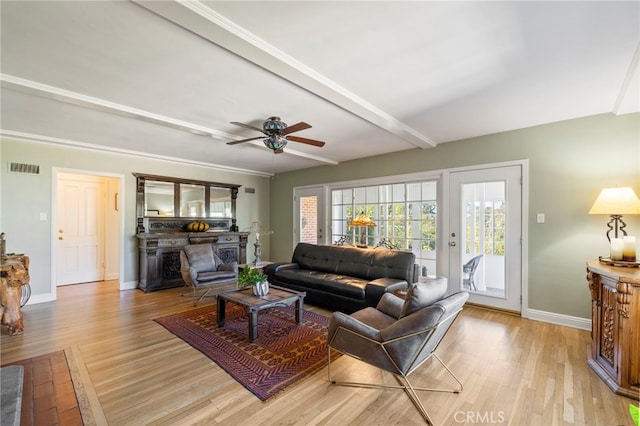 living area with a fireplace, visible vents, baseboards, light wood-style floors, and beam ceiling