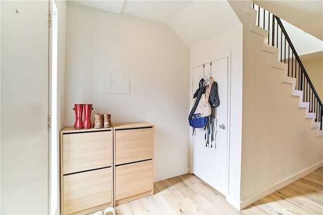 interior space with light wood finished floors, baseboards, stairway, and vaulted ceiling