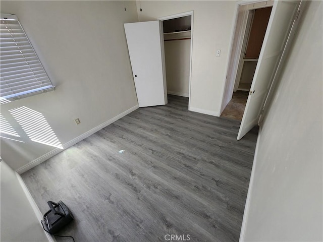 unfurnished bedroom with a closet, wood finished floors, and baseboards