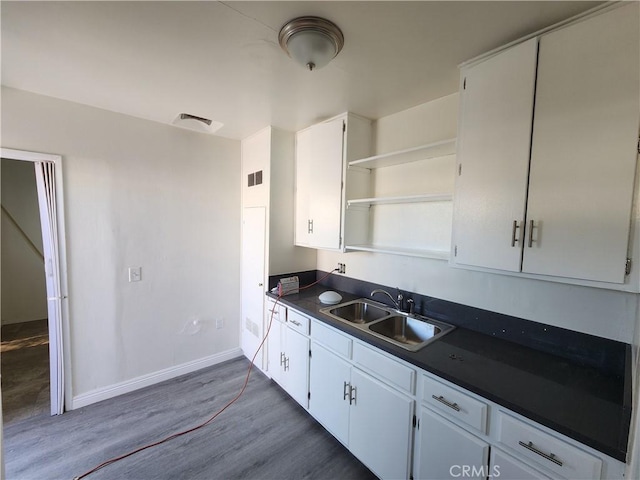 kitchen featuring open shelves, dark countertops, visible vents, white cabinets, and a sink