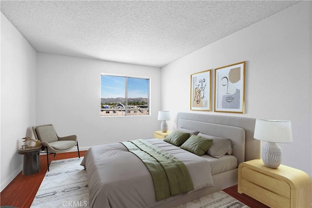 bedroom with a textured ceiling, baseboards, and wood finished floors