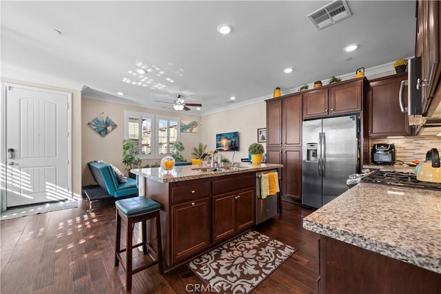 kitchen featuring crown molding, stainless steel appliances, visible vents, a sink, and an island with sink