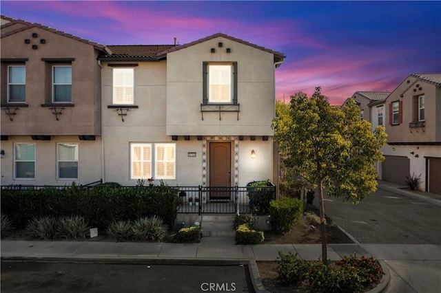 view of front of property with a garage, a tiled roof, decorative driveway, and stucco siding