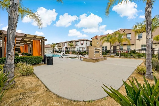 view of home's community with a swimming pool, a patio area, fence, and a residential view