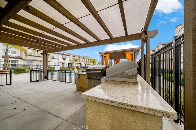 view of patio featuring a residential view, fence, grilling area, and an outdoor kitchen