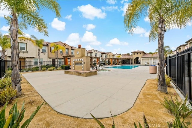 community pool featuring a residential view, fence, and a patio