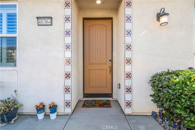 doorway to property featuring stucco siding