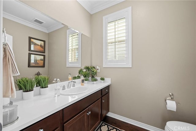 bathroom featuring toilet, vanity, visible vents, baseboards, and ornamental molding