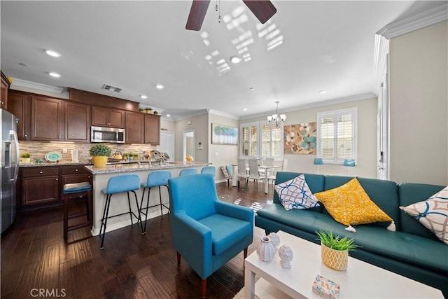 living room with visible vents, ornamental molding, dark wood-style flooring, ceiling fan with notable chandelier, and recessed lighting