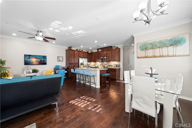 dining room with recessed lighting, dark wood finished floors, crown molding, and ceiling fan with notable chandelier