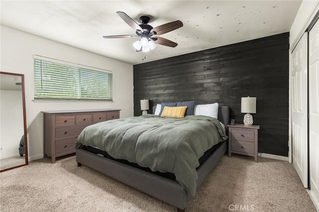 bedroom featuring light carpet, an accent wall, wood walls, and baseboards