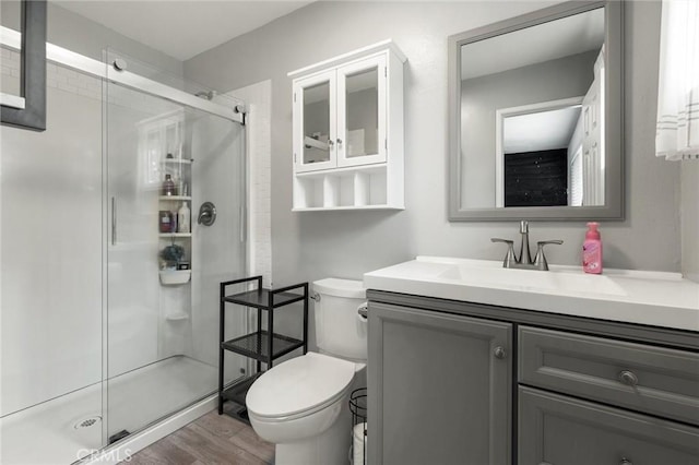 full bath with vanity, wood finished floors, a shower stall, and toilet