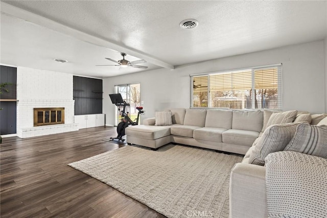 living room with visible vents, a ceiling fan, wood finished floors, a textured ceiling, and a brick fireplace