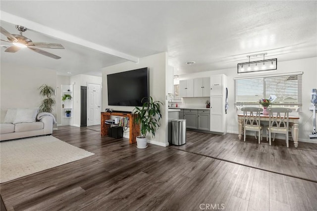 living room with beam ceiling, dark wood finished floors, baseboards, and ceiling fan