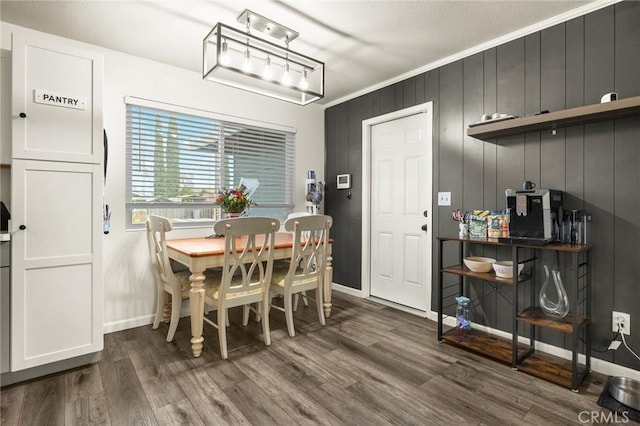 dining space with crown molding, baseboards, and wood finished floors