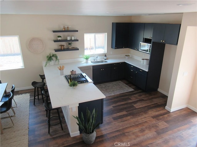 kitchen with light countertops, dark cabinetry, a sink, and a healthy amount of sunlight