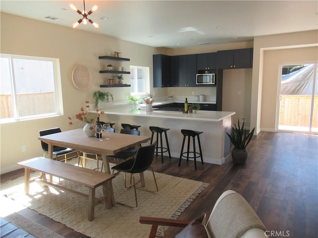 dining area featuring a chandelier, dark wood-style flooring, visible vents, and baseboards