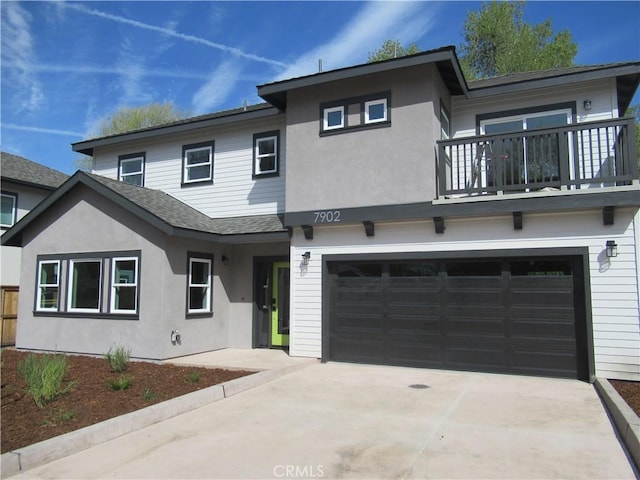 view of front of home featuring stucco siding, a shingled roof, a balcony, a garage, and driveway