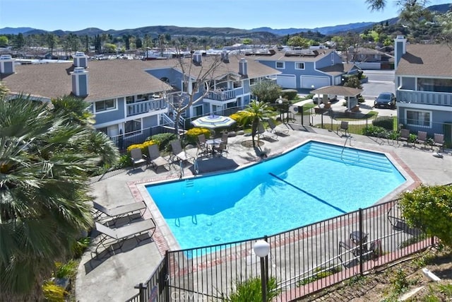 pool featuring a patio area, a residential view, fence, and a mountain view