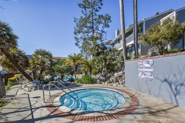 view of swimming pool featuring a patio area, fence, and a community hot tub