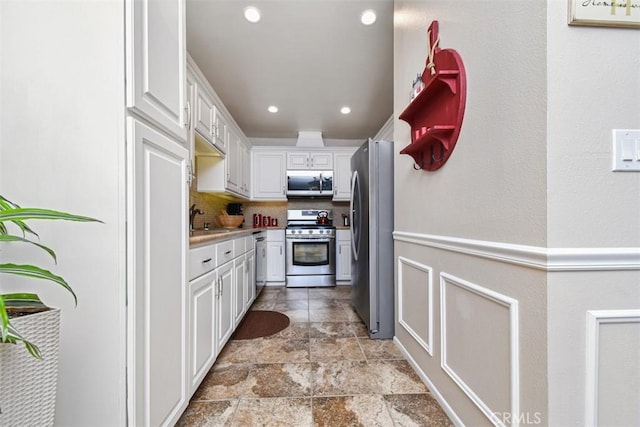 kitchen with tasteful backsplash, light countertops, appliances with stainless steel finishes, white cabinetry, and a sink