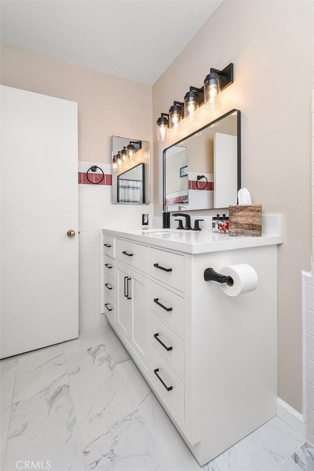 bathroom featuring marble finish floor, tile walls, and vanity