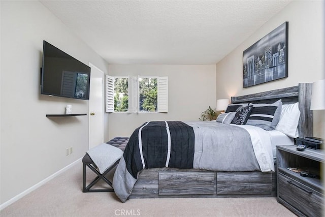 bedroom featuring light carpet, a textured ceiling, and baseboards