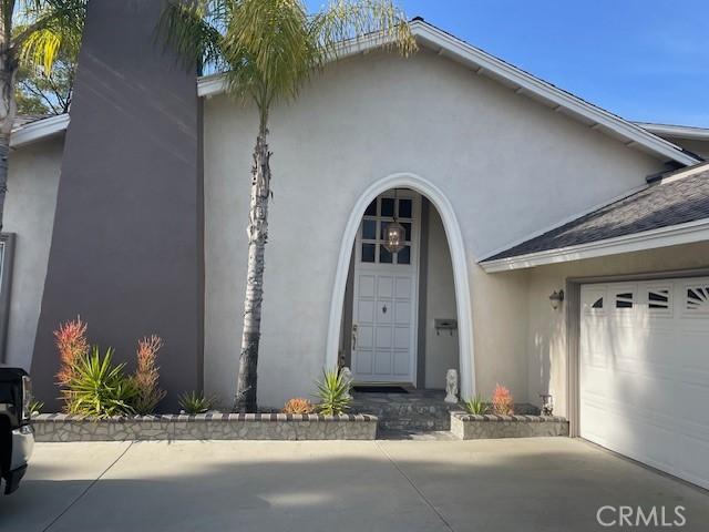 doorway to property with a garage, driveway, and stucco siding