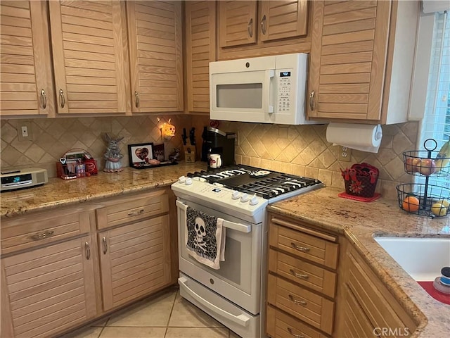 kitchen with light stone counters, light tile patterned floors, decorative backsplash, light brown cabinetry, and white appliances